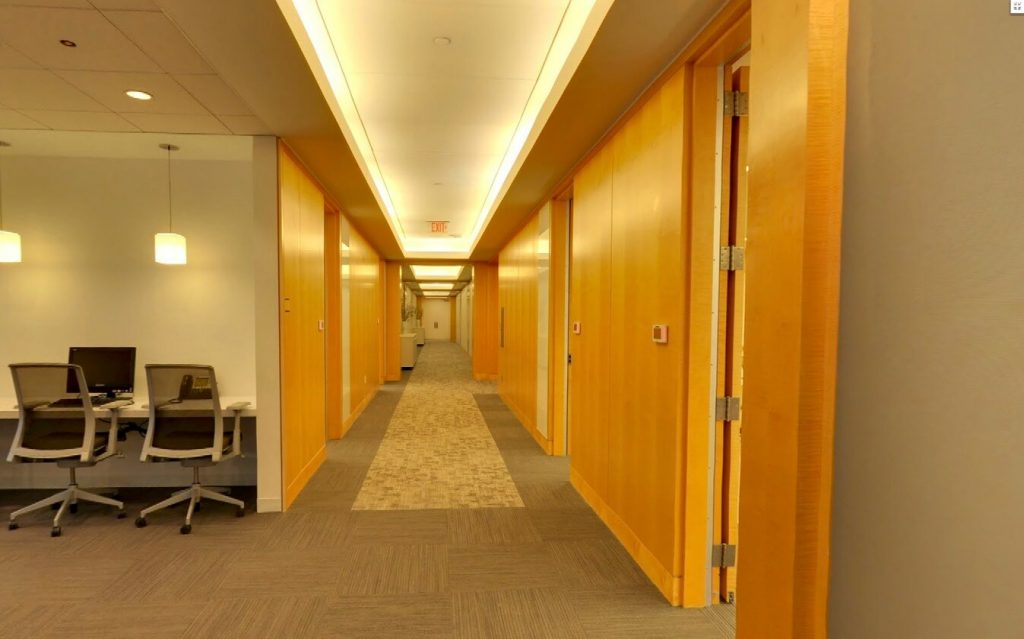 A long hallway with wooden paneling and carpet.