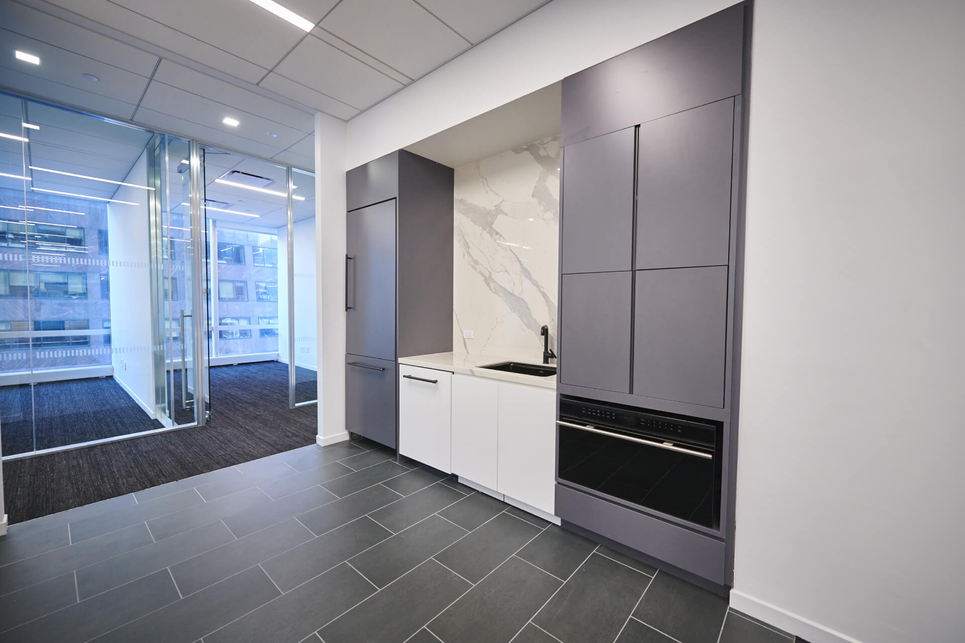 A kitchen with grey cabinets and white counters.